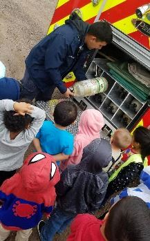 Firefighter Marco Chairez showing Engine 6 fire equipment to children at Kids Planet II.